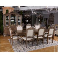 a dining room table with chairs and a china cabinet in the middle is surrounded by an area rug