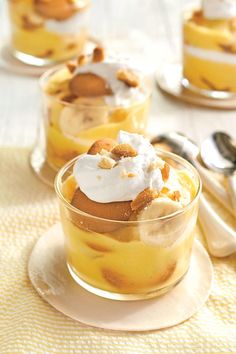 two desserts with bananas and whipped cream in small glass dishes on a yellow tablecloth