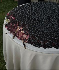 a large chocolate cake on top of a table covered in blueberries and pink flowers