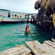 a woman swimming in the ocean next to a dock with boats and people on it