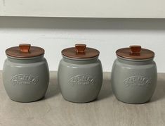 three gray canisters with copper lids are sitting on a countertop next to each other