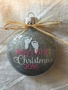 a baby's first christmas ornament hanging from a ribbon