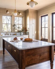 a large kitchen island in the middle of a wood floored room with two windows