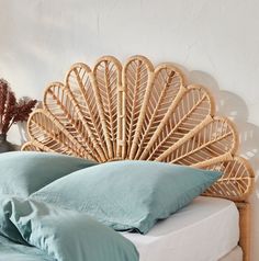 a wicker headboard with blue pillows in a white room next to a bed