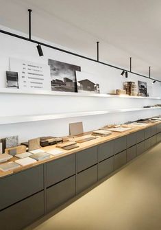 a long counter with many books on it in a room that has white walls and ceilings