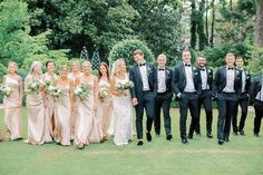 a group of people standing next to each other in front of some trees and bushes