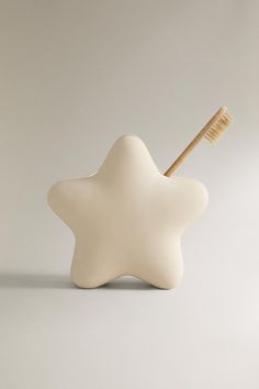 a toothbrush holder with a star shaped tooth brush in it's mouth, against a white background