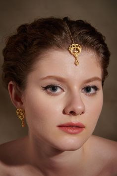 Inspired from the Rococo Era, the tikka headpiece features intricate floral patterns. It is handcrafted using ancient filigree and embossing techniques finished in 18K matt gold plating. The ornate motifs add to the uniqueness and grandeur of the piece. The tikka is perfectly suited to match with traditional outfits. Whether it's a sangeet or a cocktail, style with desi, fusion and contemporary looks. Pair it with matching earrings and choker to complete the occasion look. Chain Length: 10 cm Mo Elegant Ceremonial Tikka With Tilla Detailing, Elegant Ceremonial Tikka With Intricate Design, Elegant Ceremonial Tikka, Elegant Ceremonial Tikka For Navratri, Elegant Ceremonial Tikka For Diwali, Bohemian Tilla Tikka For Diwali, Temple Jewelry Tikka With Intricate Design, Ceremonial Elegant Cutdana Tikka, Traditional Adjustable Tikka For Ceremonial Occasions