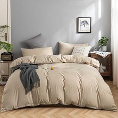 a bed with beige sheets and pillows in a room