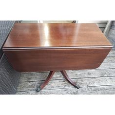 a wooden desk sitting on top of a wooden floor next to a metal object with wheels