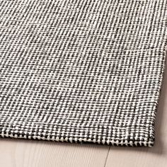 a black and white checkered rug sitting on top of a wooden floor