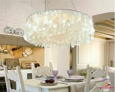 a chandelier hanging from the ceiling over a dining room table with white chairs