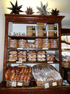 breads and pastries are displayed on shelves in a bakery display case with star decorations