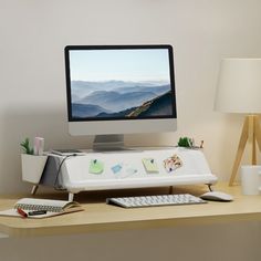 a desktop computer sitting on top of a wooden desk next to a lamp and other items