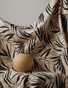 a wooden vase sitting on top of a black and white cloth covered chair with palm leaves