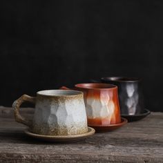 three coffee cups sitting on top of a wooden table