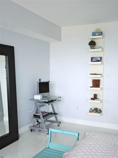 a room with a bed, desk and chair in it's corner area next to a large mirror