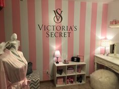 a pink and white striped wall in a girls's room with a vanity, dressing table, and mirror