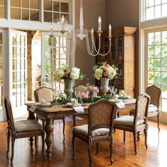 a dining room table with chairs and chandelier in the middle of an open floor plan