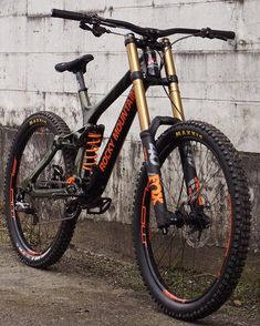 a mountain bike parked in front of a building with graffiti on the side and orange lettering