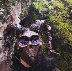 a person wearing a creepy mask with moss growing on it