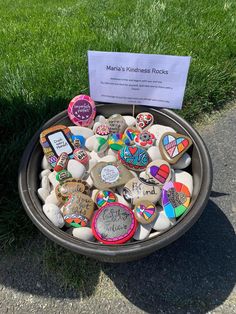 a bowl filled with lots of rocks and magnets next to a sign that reads, man's kindness rock