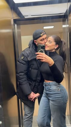 a man and woman taking a selfie in an elevator with their hands on each other's hips