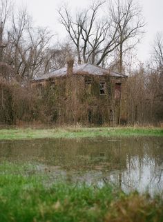 an old abandoned house sitting next to a pond