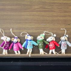 five little mice in sweaters are lined up on a shelf with string attached to them