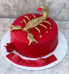 a red and white cake with a gold scorpion on top