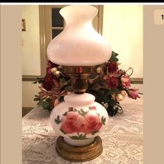 an antique lamp with roses on it sitting on a table