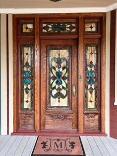 the front door is decorated with stained glass and wood trims, along with a welcome mat