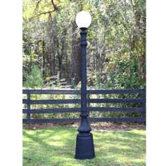 a lamp post in the grass near a fence