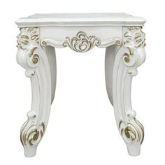 an ornate white table with gold accents on the top and bottom shelf, against a white background