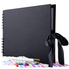 a black binder with colored crayons and a bow on it next to some markers