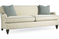 a white couch with two blue pillows on it's arms and backrests