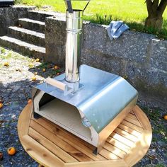 an outdoor pizza oven sitting on top of a wooden table