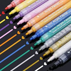 several different colored markers are lined up on a black surface