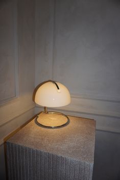 a lamp sitting on top of a table next to a wall