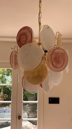 a chandelier hanging from the ceiling in front of a window with lots of dishes on it