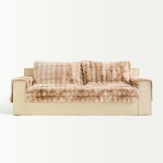 a beige couch with two pillows on it's back and the seat upholstered