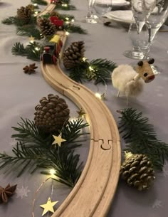 a toy train set up on a table with pine cones and christmas decorations around it