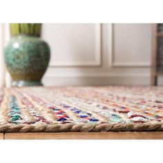 a close up of a rug with a vase in the background