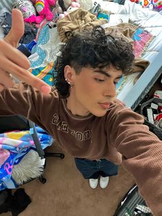 a young woman with curly hair standing in front of a pile of clothes