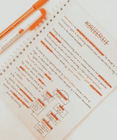 an orange pen sitting on top of a paper