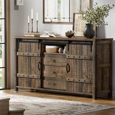 a wooden cabinet with drawers and candles on top of it in front of a mirror