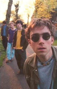 a group of young men standing next to each other on a sidewalk with trees in the background