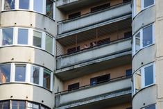 an apartment building with several balconies and people in the windows looking out from their balconies