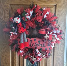 a red and black mesh wreath with a ladybug on it that says welcome