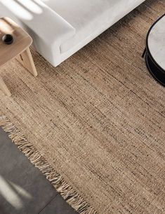 a white couch sitting next to a table on top of a rug